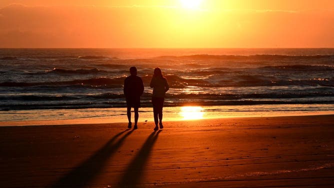 FILE PHOTO: People walk along the beach as the sun rises over the Gulf of Mexico in South Padre Island, Texas, on November 16, 2023.