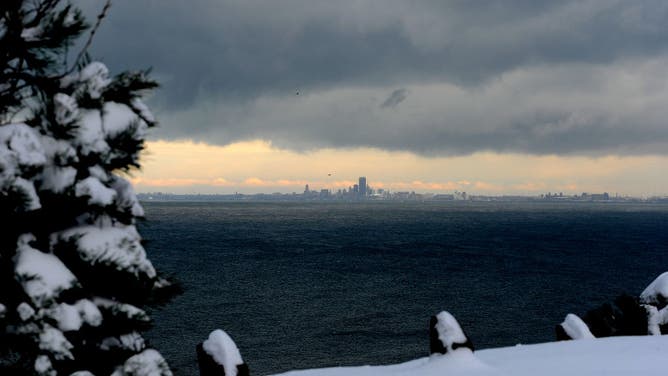 Lake effect snow clouds hang over Lake Erie and the Buffalo skyline December 1, 2024 as seen from Hamburg, New York.