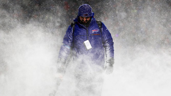 A grounds crew member blows snow off the field during a timeout in a game between the Buffalo Bills and the San Francisco 49ers at Highmark Stadium on December 01, 2024 in Orchard Park, New York.