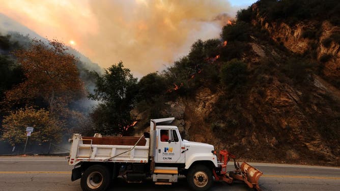 Heavy equipment removes boulders as a mountainside burns while the Franklin Fire grows in Malibu, California, on December 10, 2024.