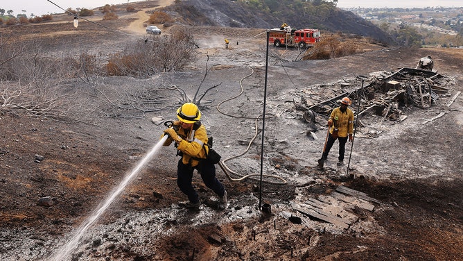 Firefighters extinguish hotspots as the Franklin fire burns around Malibu, California, on December 11, 2024.