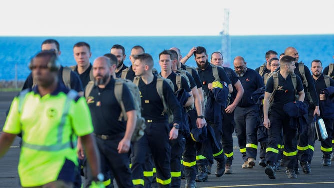 Members of the French Civil protection and French firefighters walk on the tarmac following their landing aboard the A440M military aircraft, as part of an emergency response to bring aid to the small French Indian Ocean territory of Mayotte, almost cut off from the world after the passage of cyclone Chido, at the French Air Force Base 181 Saint-Denis-La Reunion "Lieutenant Roland Garros" in Sainte-Marie, on the French Indian Ocean island of La Reunion, on December 15, 2024.