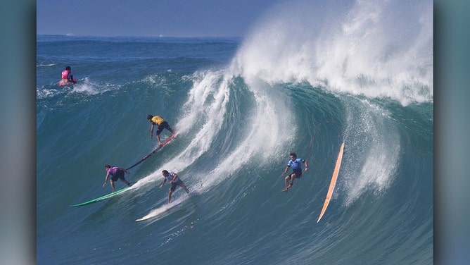 Hawaiian surfer Mark Healy (R) wipes out near other competitors during the 2024 Rip Curl Eddie Aikau Big Wave invitational on the north shore of Oahu, Hawaii, on December 22, 2024.