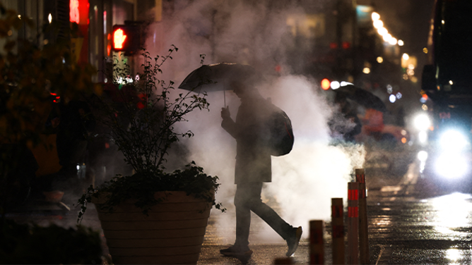 FILE - A person holds an umbrella as they walk under the rain in a street of the Manhattan borough of New York City on November 21, 2024. (Photo by CHARLY TRIBALLEAU / AFP) (Photo by CHARLY TRIBALLEAU/AFP via Getty Images)