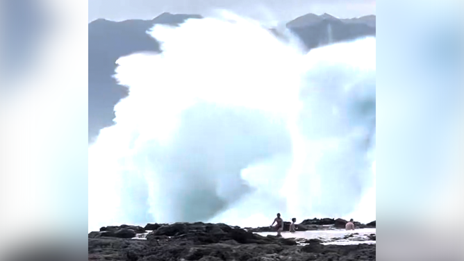 Waves about to crash onto the three men.