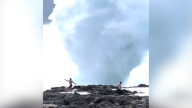 Waves about to crash onto the three men.