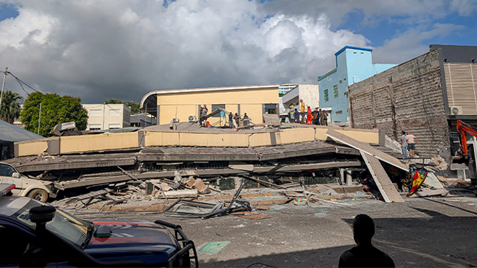 Rescue workers are seen at the site of a collapsed building after a powerful earthquake struck Port Vila, the capital city of Vanuatu, on December 17, 2024. A powerful earthquake hit the Pacific island of Vanuatu on December 17, smashing buildings in the capital Port Vila including one housing the US and other embassies, with a witness telling AFP of bodies seen in the city. (Photo by AFP) (Photo by STR/AFP via Getty Images)