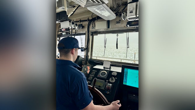 U.S. Coast Guard Seaman Stephan Dailey mans the helm as Coast Guard Cutter Bristol Bay (WTGB 102) approaches the motor vessel MANITOULIN in Buffalo, New York on Lake Erie Jan. 23, 2025. Dailey's hometown is Cleveland, Ohio only a few hours away from Buffalo, New York where they were breaking ice.