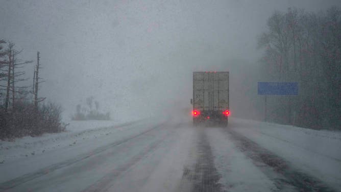 FILE - A semi-truck with hazard lights on navigates through the snow squall on I-81 on December 5, 2024 in Watertown, New York. This region in New York is experiencing the second snowstorm of the week and has been under a Winter Storm Warning for two days. (Photo by Kayla Bartkowski/Getty Images)