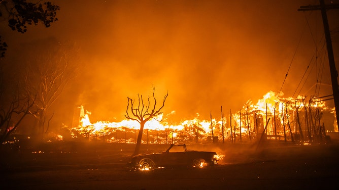 Flames from the Palisades Fire burns a car and homes during a powerful windstorm on January 8, 2025 in the Pacific Palisades neighborhood of Los Angeles, California.