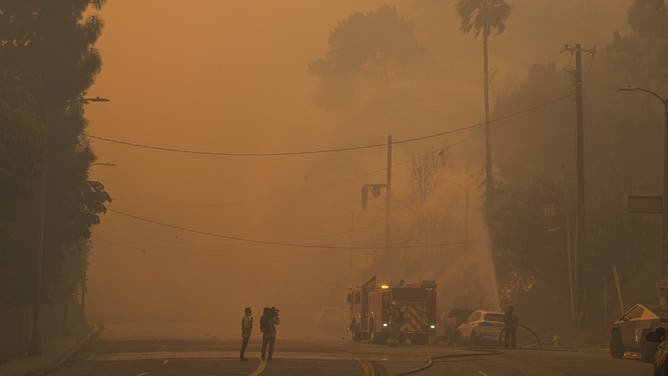 2025年1月8日、米国カリフォルニア州ロサンゼルスのパシフィック・パリセーズで住民が現場から逃げようとする中、トーランスの消防士がパリセーズ火災の消火準備をしている。