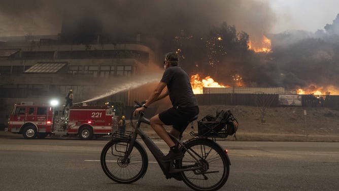 2025年1月8日、米国カリフォルニア州ロサンゼルスのパシフィック・パリセーズで住民が現場から逃げようとする中、トーランスの消防士がパリセーズ火災の消火準備をしている。