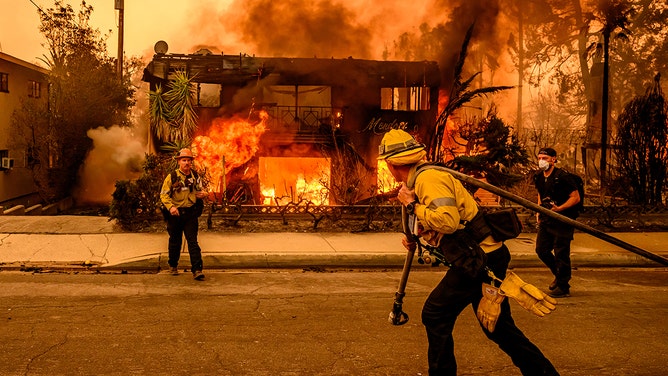 Firefighters work the scene as an apartment building burns during the Eaton fire in the Altadena area of Los Angeles county, California on January 8, 2025.