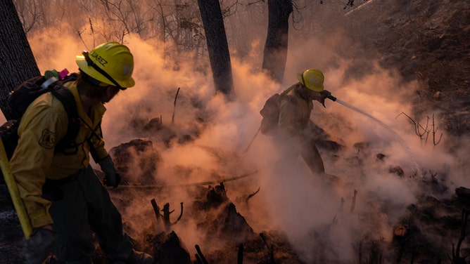 Firefighters mop up hot spots near the major communications towers on Mount Wilson, as the Eaton Fire continues to burn on January 9, 2025 near Altadena, California.
