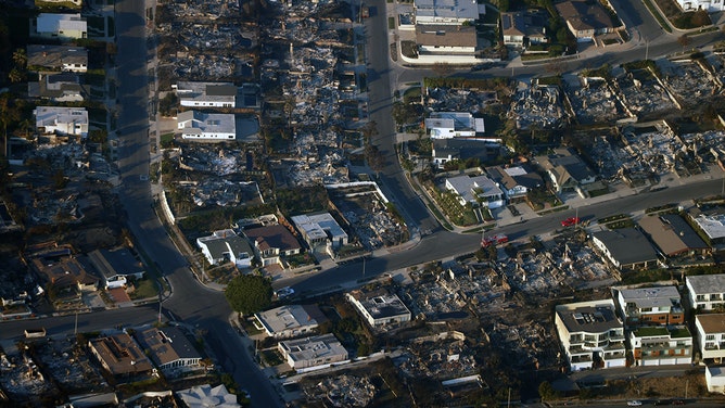 この航空写真は、2025 年 1 月 10 日にカリフォルニア州ロサンゼルスのパシフィック パリセーズ地区にあるパリセーズ火災で破壊された家屋と、その他の無傷の家々 を示しています。