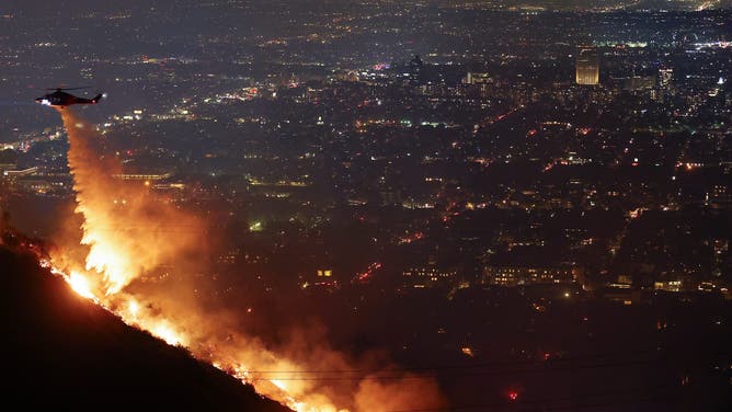 ロサンゼルス、カリフォルニア州 - 1月8日: ハリウッドヒルズの日没火災の際、消防ヘリコプターが水を投下する。 2025 年 1 月 8 日、カリフォルニア州ロサンゼルスは避難を命じられました。