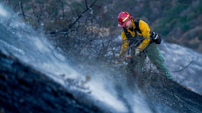 A firefighter works on a hillside during the aftermath of the Palisades Fire in the Pacific Palisades area of Los Angeles, California, US, on Sunday, Jan. 12, 2025. At least two rounds of vicious, dry Santa Ana winds are expected to blast through Southern California early this week, bringing powerful gusts that will challenge fire crews struggling to contain two destructive blazes and likely force thousands more residents to evacuate. Photographer: Kyle Grillot/Bloomberg via Getty Images