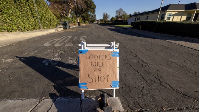 ALTADENA CALIFORNIA - JANUARY 12: A sign reading 'Looters will be shot' stands in a mandatory evacuation zone at the Eaton Fire on January 12, 2025 in Altadena, California. The death toll from the Eaton Fire rose to 16 today as search and rescue teams go through the ruins of thousands of homes. More than 7,000 structures, mostly homes, were damaged or destroyed as a powerful Santa Ana wind event pushed flames farther into the city than even many fire experts expected. (Photo by David McNew/Getty Images)