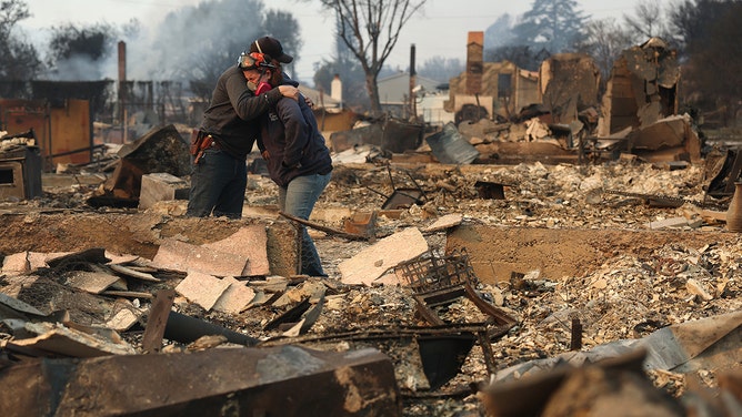 Khaled Fouad, left, and Mimi Laine embrace as they inspect a family member's property that was destroyed by Eaton Fire on January 9, 2025 in Altadena, California.