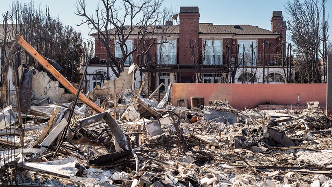 A home completely destroyed, while the house behind it is untouched along Toyopa Street in Pacific Palisades on Monday, January 13, 2025.