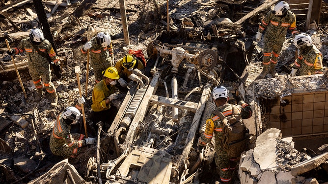 Mexican Urban Search and Rescue comb through the ruins of an automobile and beachfront home where victims of the Los Angeles fires are reportedly buried, in Malibu, California, on January 14, 2025.