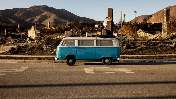 A blue Volkswagen van sits intact on a street amid homes destroyed by the Palisades Fire in Malibu, California, on January 15, 2025.