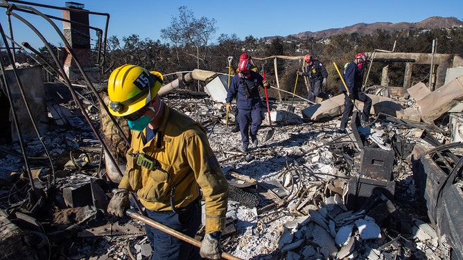 Los Angeles Fire Fighters and Sacramento Fire Fighters Urban Search &amp; Rescue team inspect a burned house from the Palisades Fire in the Pacific Palisades neighborhood on January 16, 2025 in Los Angeles, California.