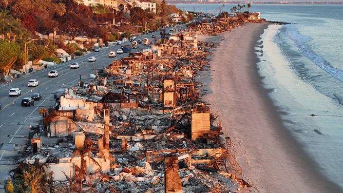 An aerial view of repair vehicles at sunset passing near beachfront homes that burned in the Palisades Fire as wildfires cause damage and loss through the LA region on January 15, 2025 in Malibu, California.