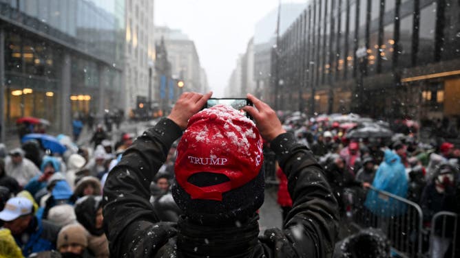 An attendee takes a photo while standing in the snow outside a rally with US President-elect Donald Trump, not pictured, at Capital One Arena ahead of the 60th presidential inauguration in Washington, DC, US, on Sunday, Jan. 19, 2025.