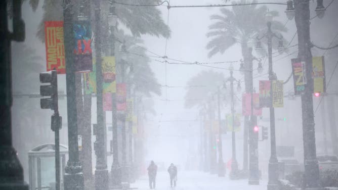 2025年1月21日、ルイジアナ州ニューオーリンズで、雪に覆われたカナル・ストリートを歩く人々。