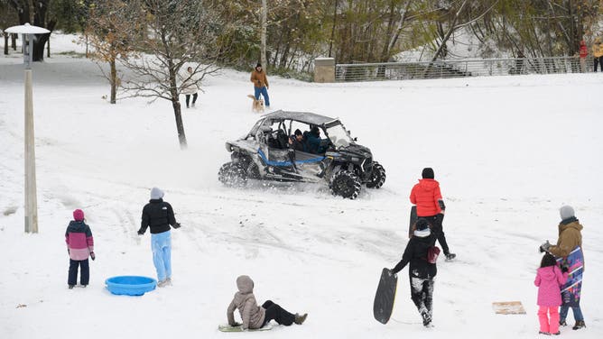 An ATV drives past residents sledding in the snow during a winter storm in Houston, Texas, US, on Tuesday, Jan. 21, 2025.