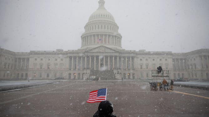 An American flag is held in the snow outside the U.S. Capitol Building on January 19, 2025 in Washington, DC.