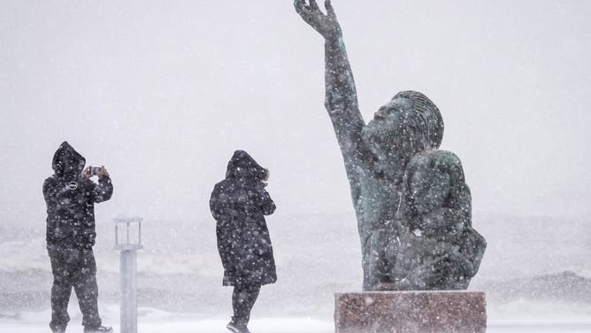 GALVESTON, TEXAS - JANUARY 21: People take photos of the 1900 Storm memorial sculpture on Seawall Blvd. during an icy winter storm on Tuesday, Jan. 21, 2025 in Galveston.