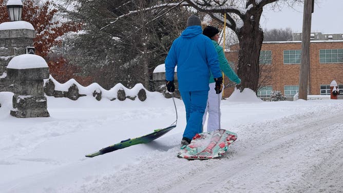 People pull sleds behind them through snow in Louisville, Kentucky.