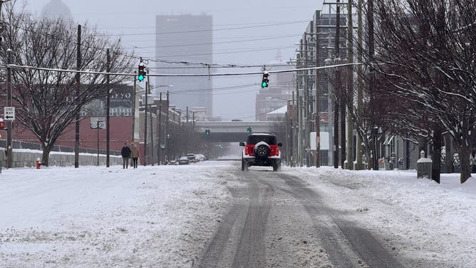 A car drives down a snowy road in Louisville, Kentucky.