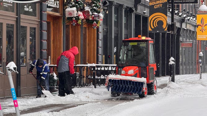 A tractor plows snow from Louisville roads on Sunday.