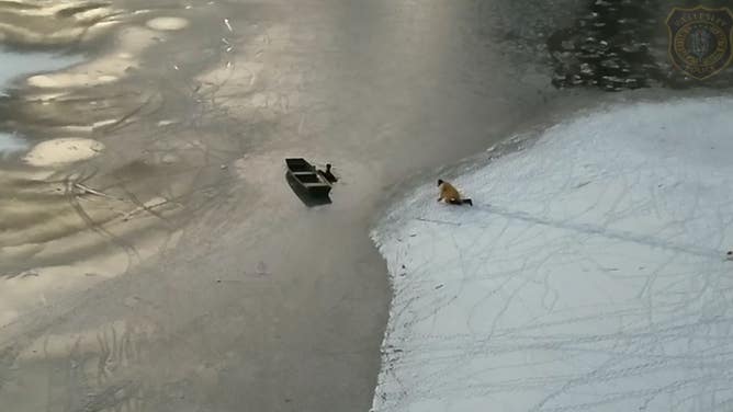 A firefighter crawls over ice to reach the man who fell into the lake.