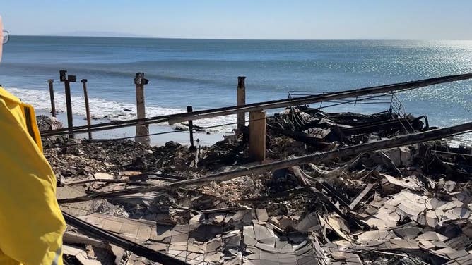 A man looks out over the wreckage of his home from the Palisades Fire.