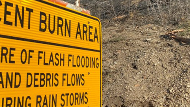 This image shows a sign warning of the flash flood and debris flow risk in a recent burn scar area in California.