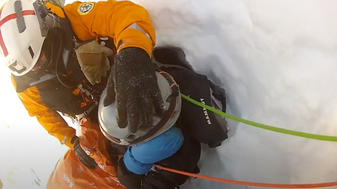 A rescuer places his hand on the injured climber's head.