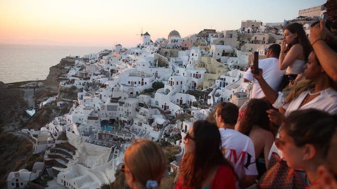 Tourists wait for the sunset in the village of Oia on the Greek island of Santorini on July 20, 2024.