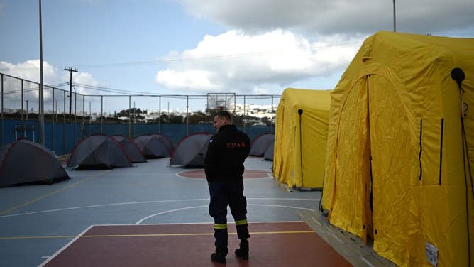 A member of Greece's firefighting service stands amongst tents set up on a basketball court for incoming rescue personnel in Fira, on the Greek Island of Santorini on February 3, 2025.