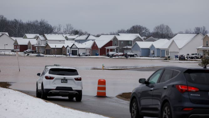 Cars park at the entrance of a flooded housing development after a rain storm on February 16, 2025 outside of Bowling Green, Kentucky.