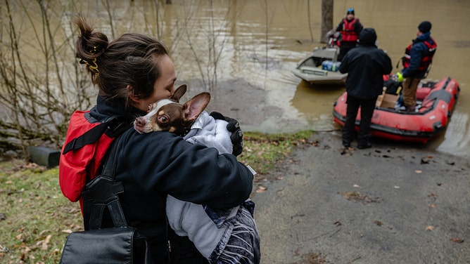 Tabitha Begley holds her dog, Tito, as the two are evacuated during a rescue and support mission in a heavily flooded area on February 18, 2025 in Leslie County, Kentucky.