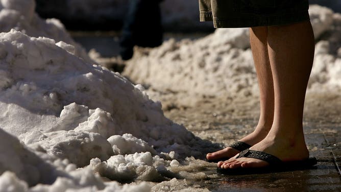 FILE: A man wearing shorts while standing next to a pile of snow.