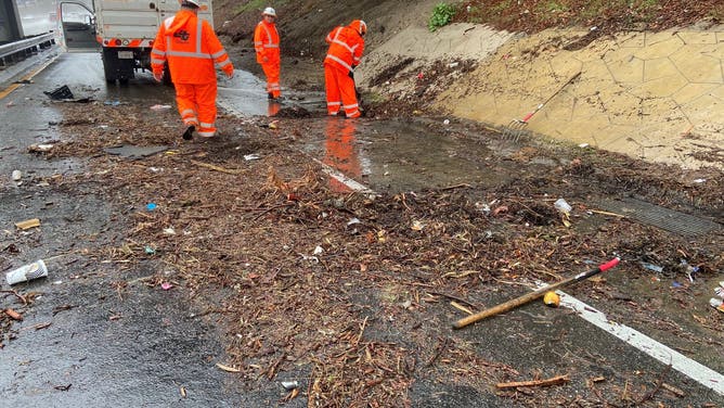 Caltrans crews remove rubble from a drain on a street in North Hollywood.