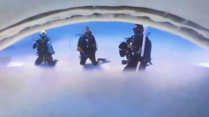 Divers seen from the perspective of a camera inside a tiger shark's mouth.