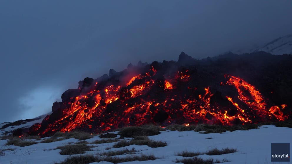 Hikers were seen walking past an erupting Mount Etna on Friday as the Sicilian volcano shot lava onto nearby snow.