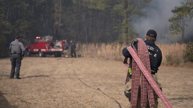 MYRTLE BEACH, SOUTH CAROLINA - MARCH 02: A firefighter carries a hose in the Carolina Forest neighborhood on March 2, 2025 in Myrtle Beach, South Carolina