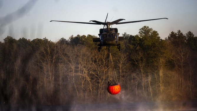 WESTHAMPTON, NEW YORK - MARCH 08: A rescue helicopter picks up water at Wild Wood Lake on March 8, 2025 in Westhampton, New York. As strong winds fueled multiple brush fires on New York's Long Island, closing roads and reportedly burning structures. (Photo by Andrew Theodorakis/Getty Images)